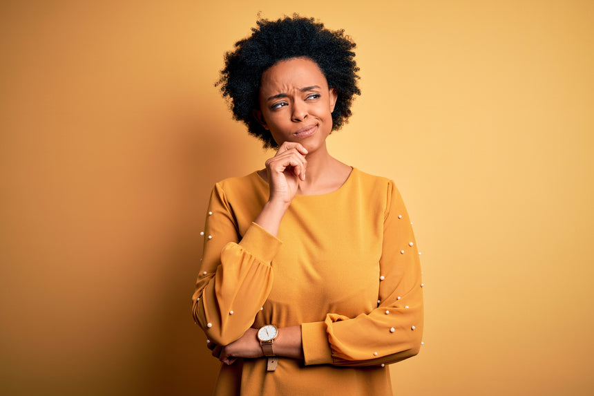 Young woman wearing casual t-shirt with hand on chin thinking about question, pensive expression. Smiling with thoughtful face.